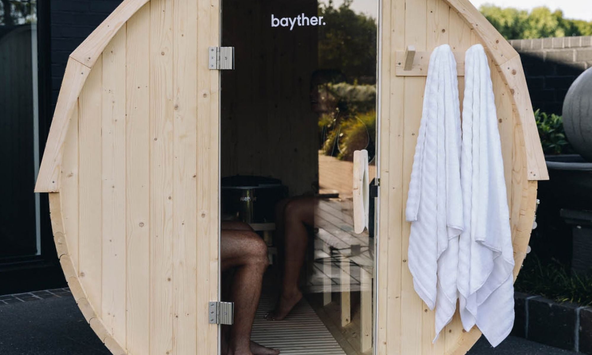 Bayther 2–4 person barrel sauna NZ with glass door installed outdoors in a backyard home sauna setting