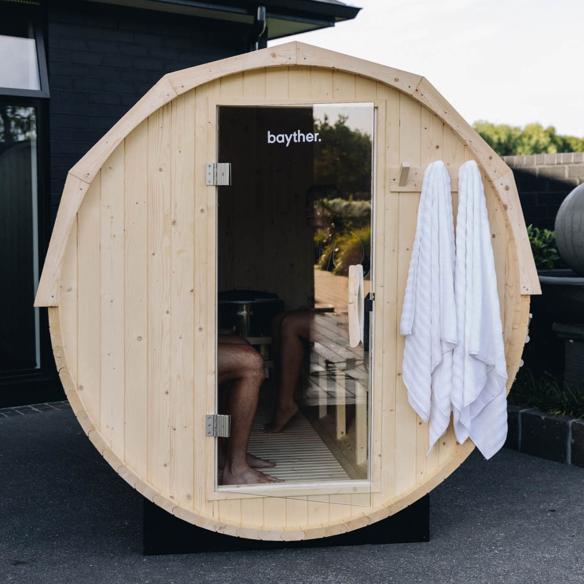 Bayther 2–4 person barrel sauna NZ with glass door installed outdoors in a backyard home sauna setting