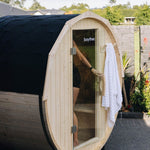 Outdoor wood fired barrel sauna with glass door and black shingle roof